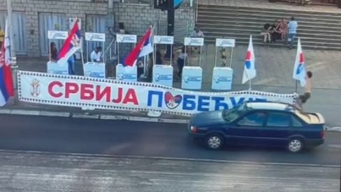 МАЛОЛЕТНИ БЛОКАДЕР НАПАО ШТАНДОВЕ СНС: Поцепао заставе и банер Србија побеђује (ВИДЕО)