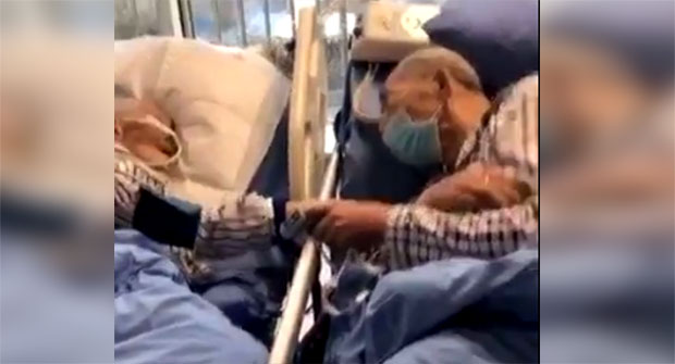 Са маскама на лицу, У БОЛНИЧКИМ КРЕВЕТИМА, држе се за руке, можда им је то ПОСЛЕДЊИ стисак? Снимак пара оболелог од опаког вируса СЛАМА СРЦА (ВИДЕО)